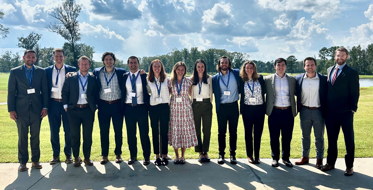 Outdoor group portrait of 13 residents at a conference.